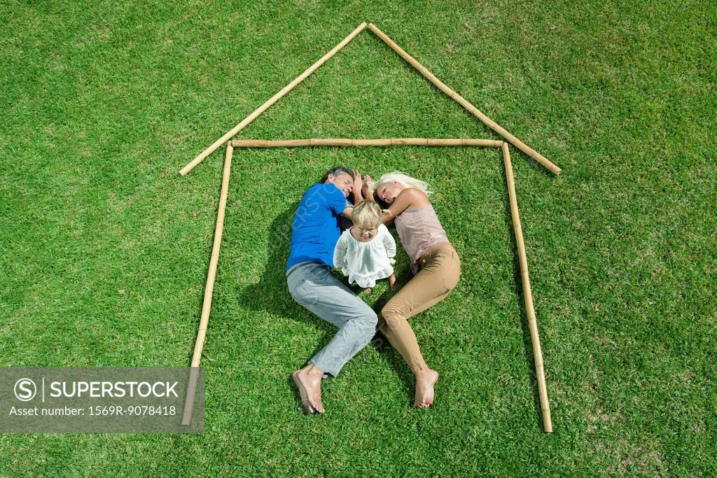 Little girl awake, parents sleeping, together within outline of house, high angle view