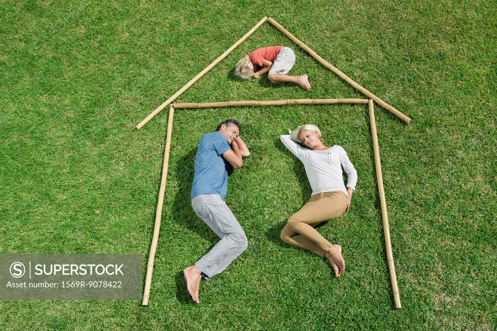 Family with one child lying on grass within outline of house, high angle view