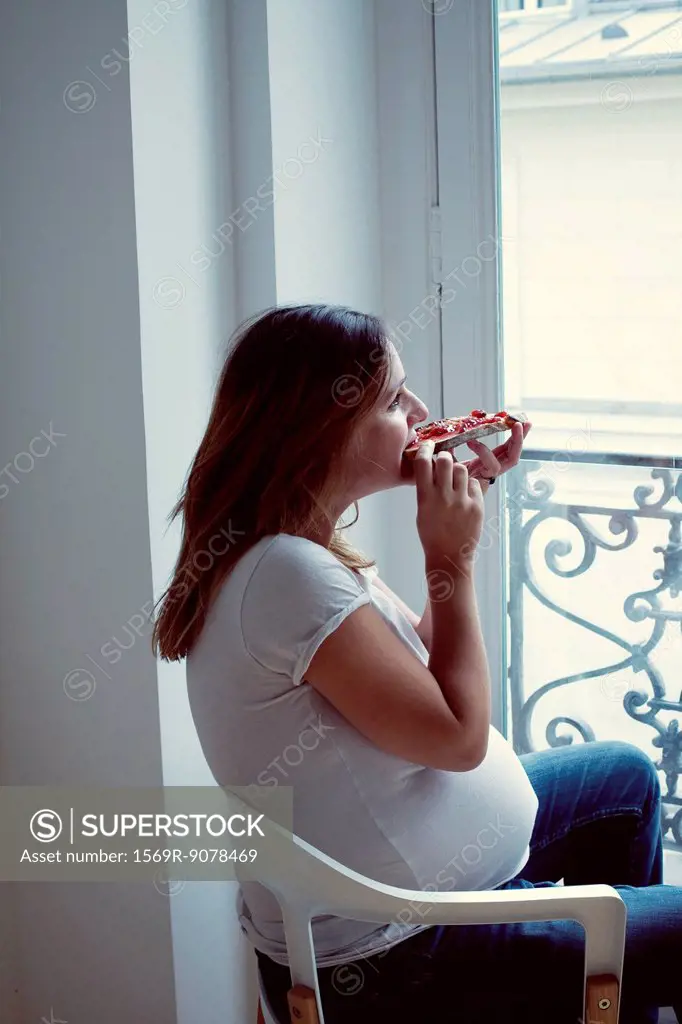 Pregnant woman eating toast with jam