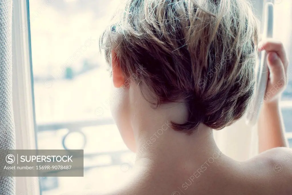 Boy looking out of window, rear view