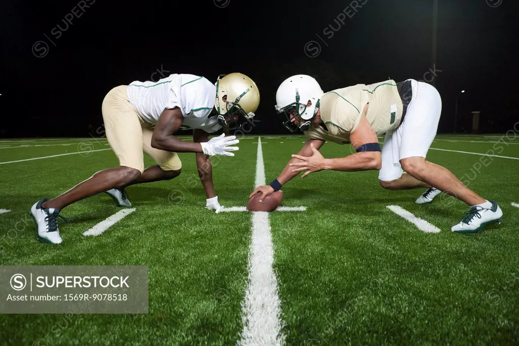 Opposing football players crouched at line of scrimmage