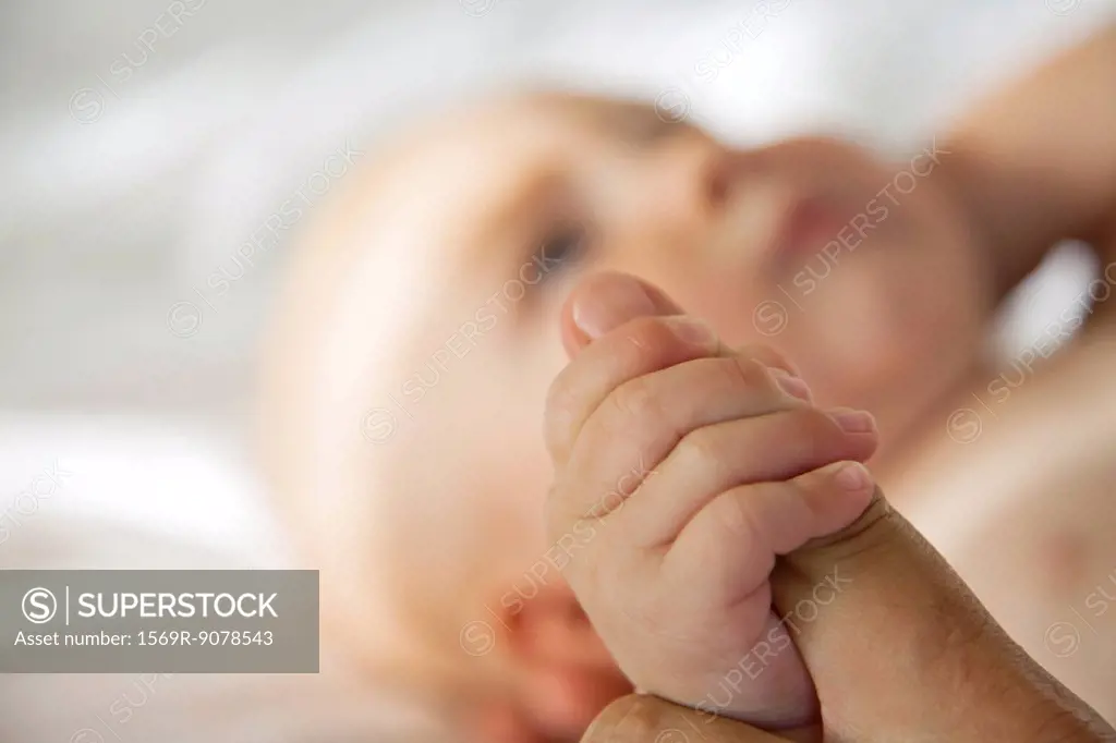 Baby holding adult´s finger