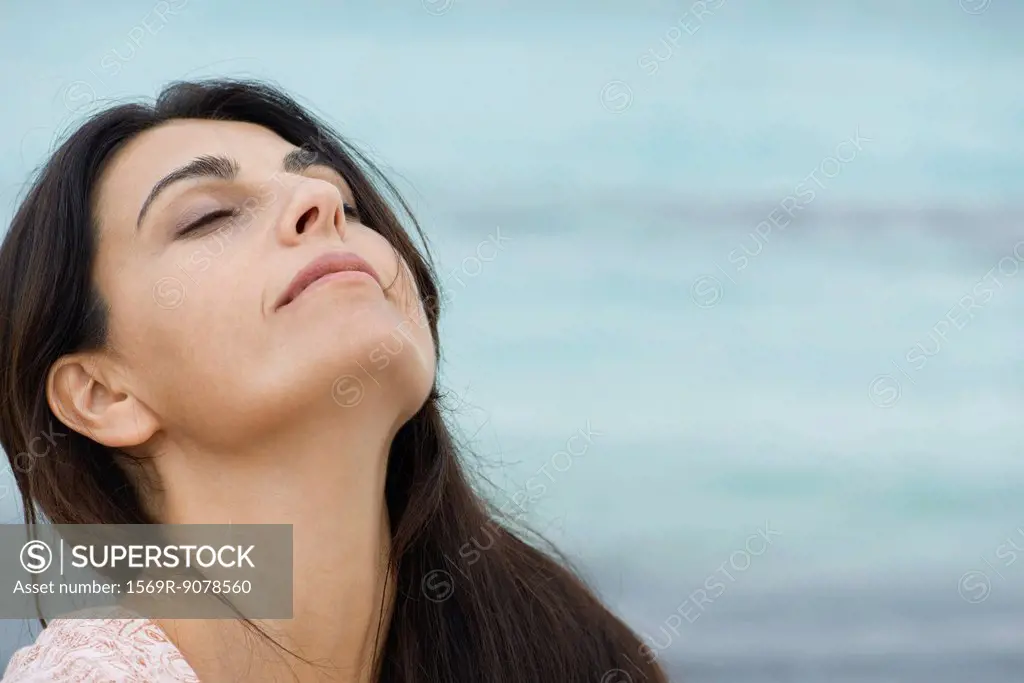 Woman breathing outdoors with head back and eyes closed