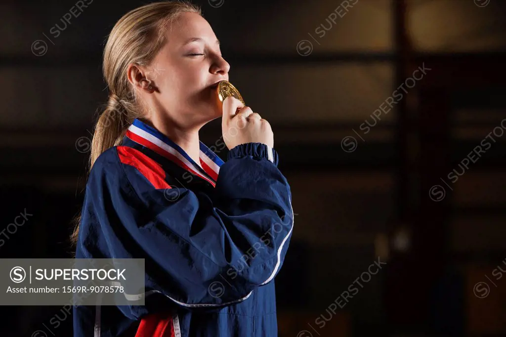 Female athlete kissing gold medal