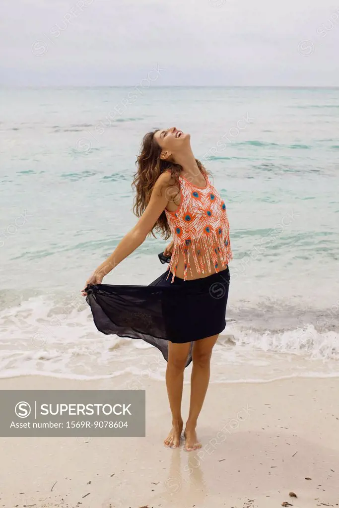 Woman standing on beach with head back and eyes closed