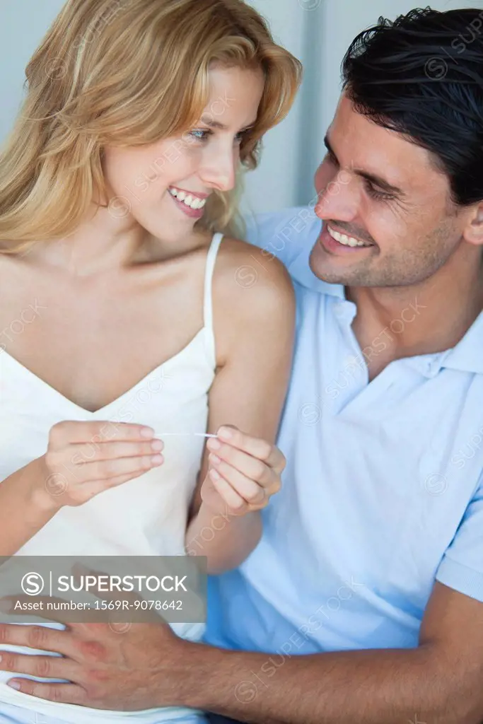 Couple looking at pregnancy test, man with hand on woman´s abdomen