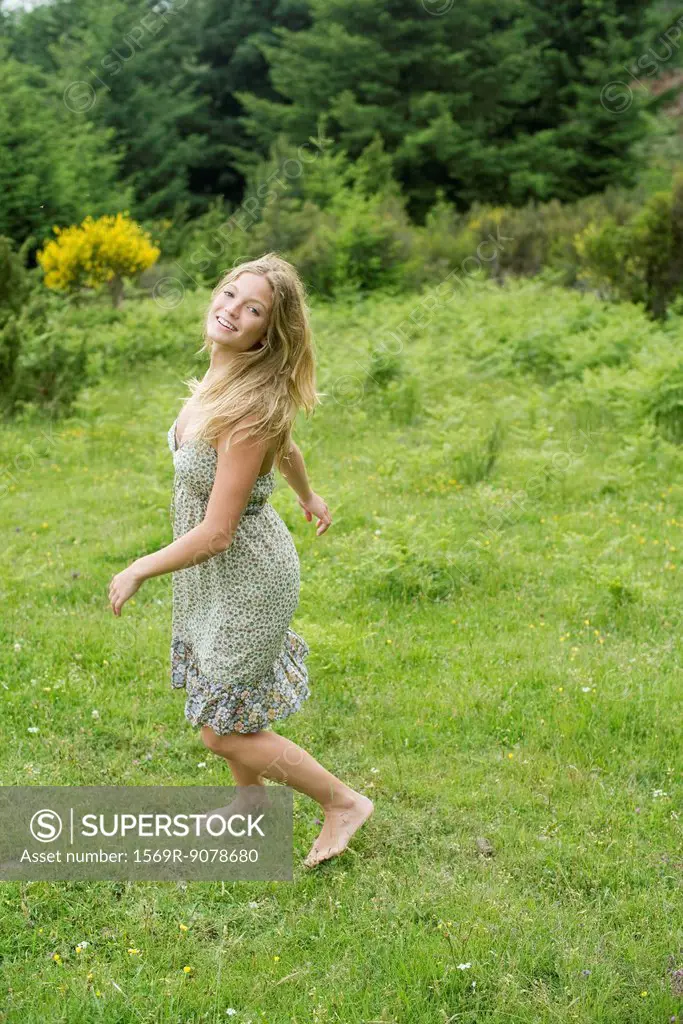 Young woman walking on meadow with barefeet