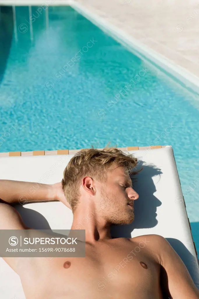 Man sunbathing beside pool