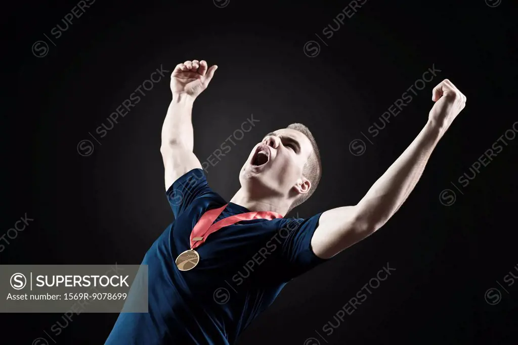 Male athlete shouting with arms raised in victory