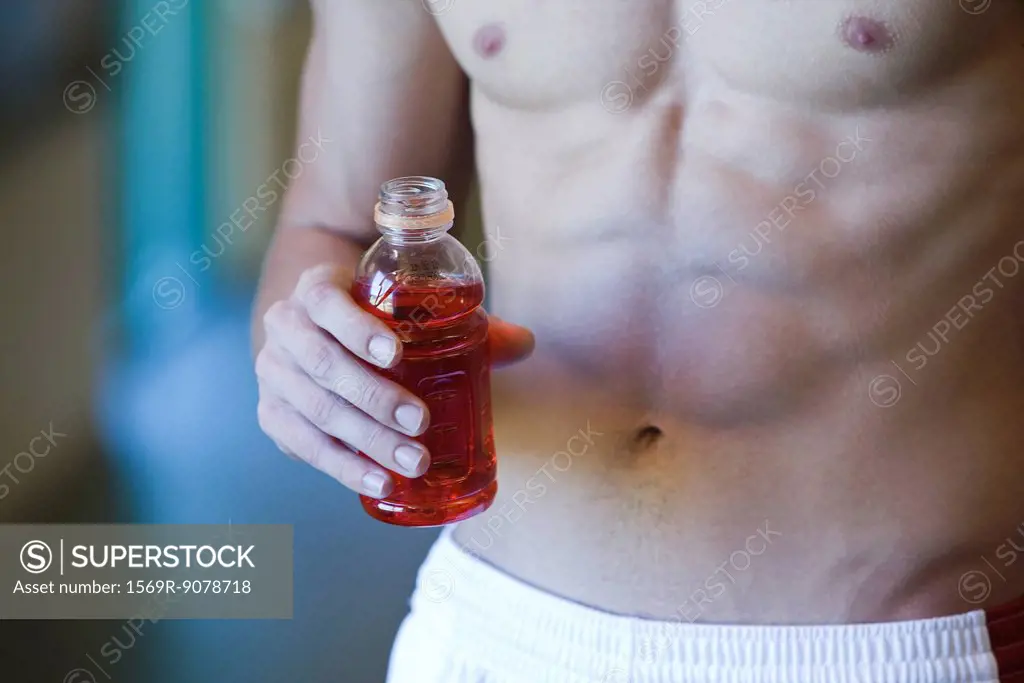 Barechested young man holding bottle of sports drink