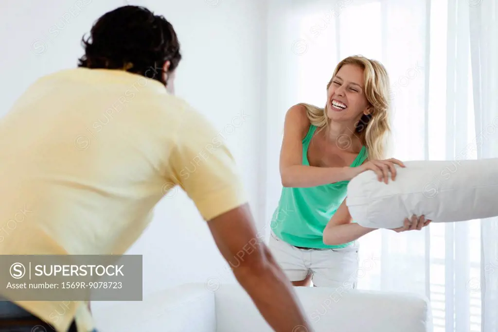 Young woman pillow fighting husband