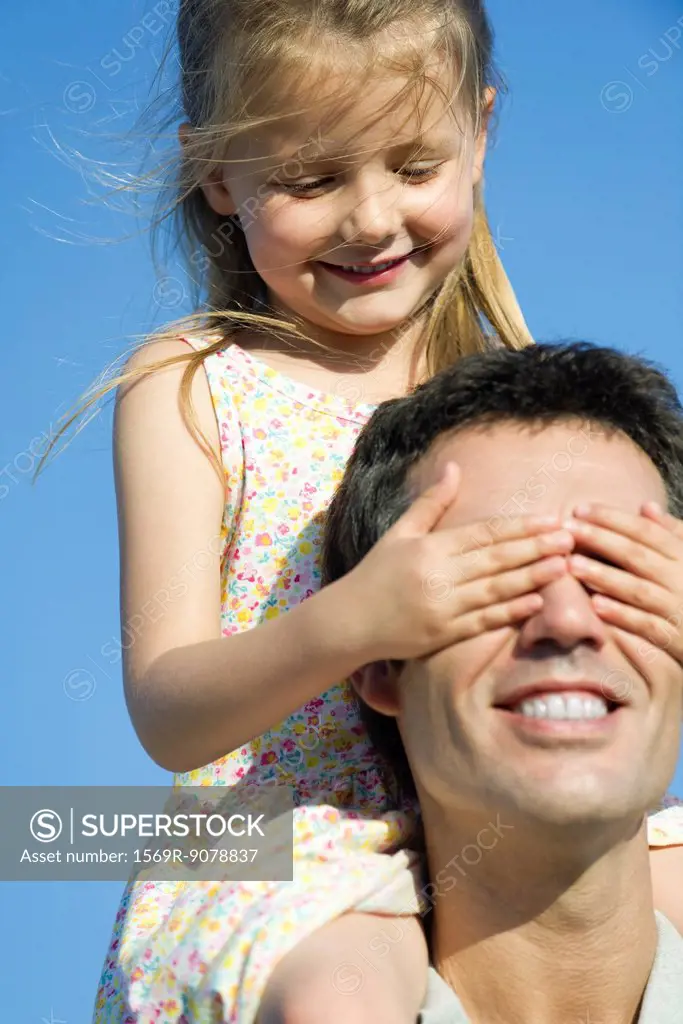 Girl covering father´s eyes with her hands