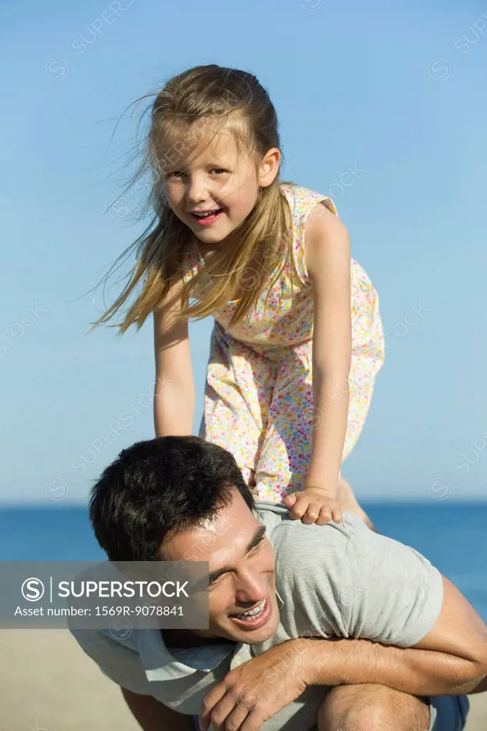 Little girl balancing on her father´s back