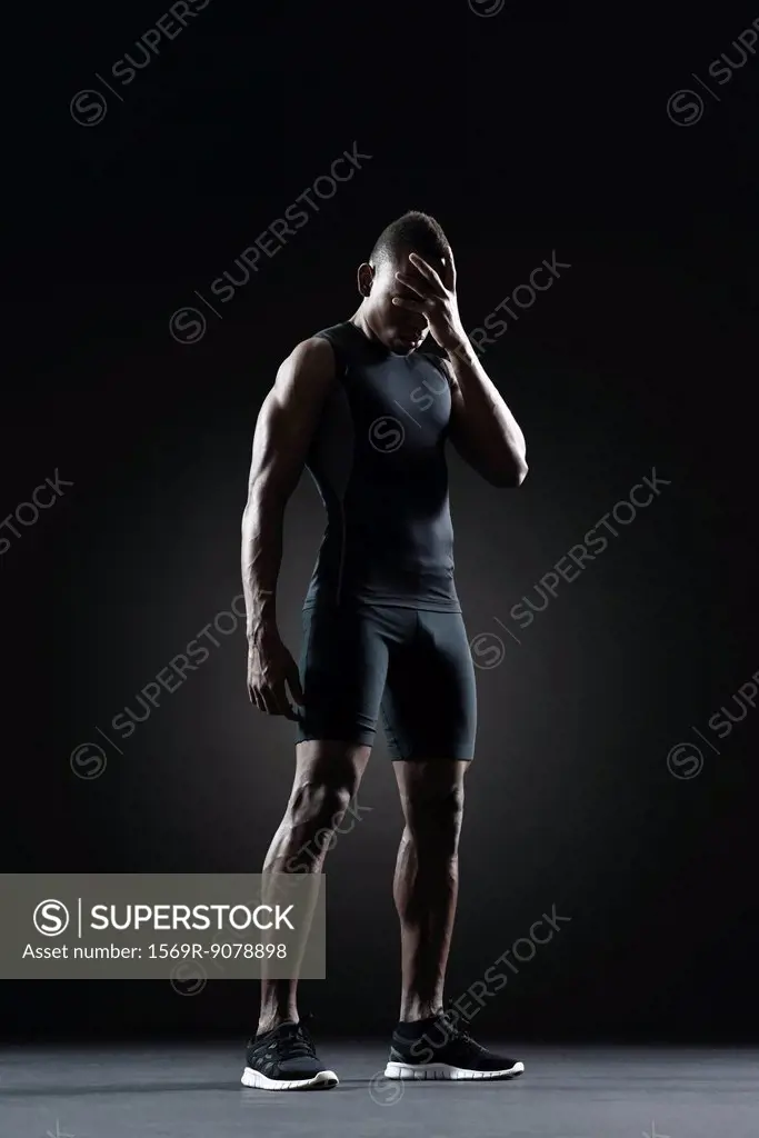 Male athlete with hand covering eyes
