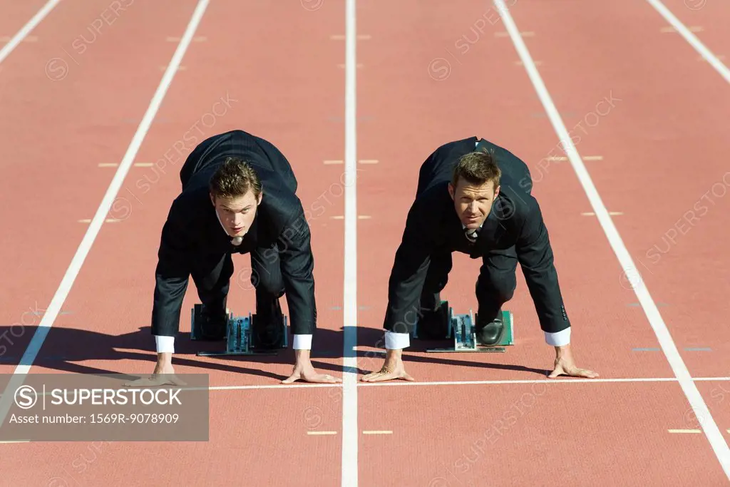 Businessmen crouched in starting position on running track