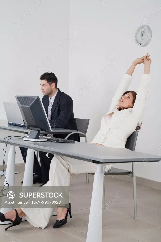Businesswoman stretching arms at desk
