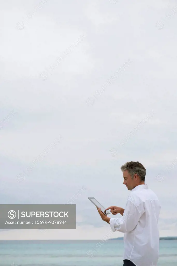 Mature man using digital tablet by ocean