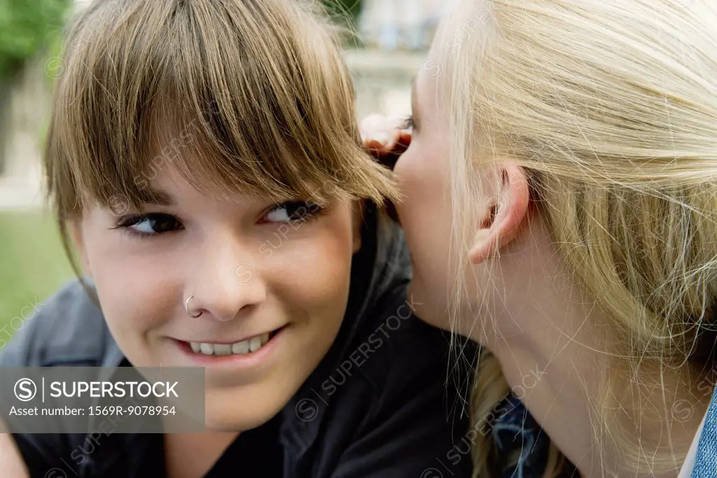 Young woman whispering in her friend´s ear