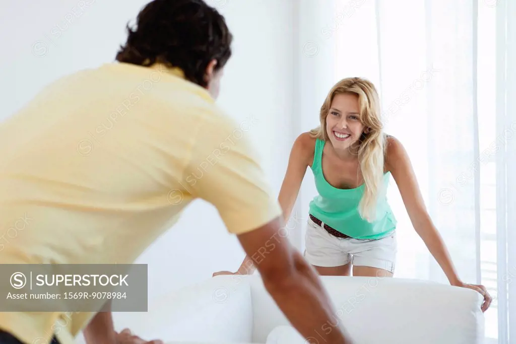 Young woman moving sofa with husband