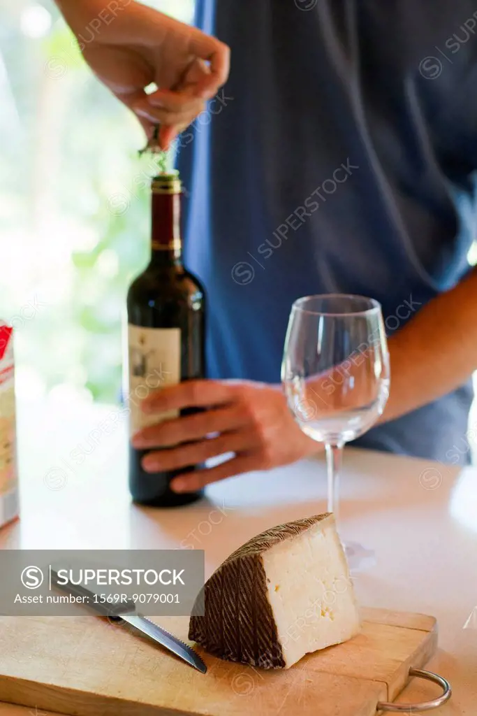 Man uncorking wine bottle, cropped