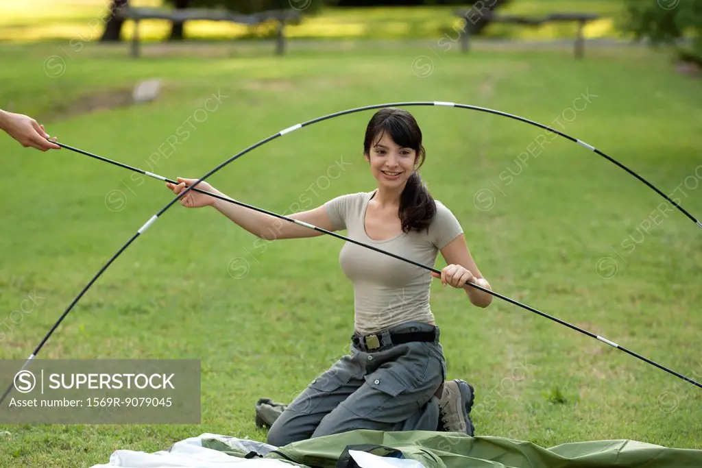Young woman putting tent poles together