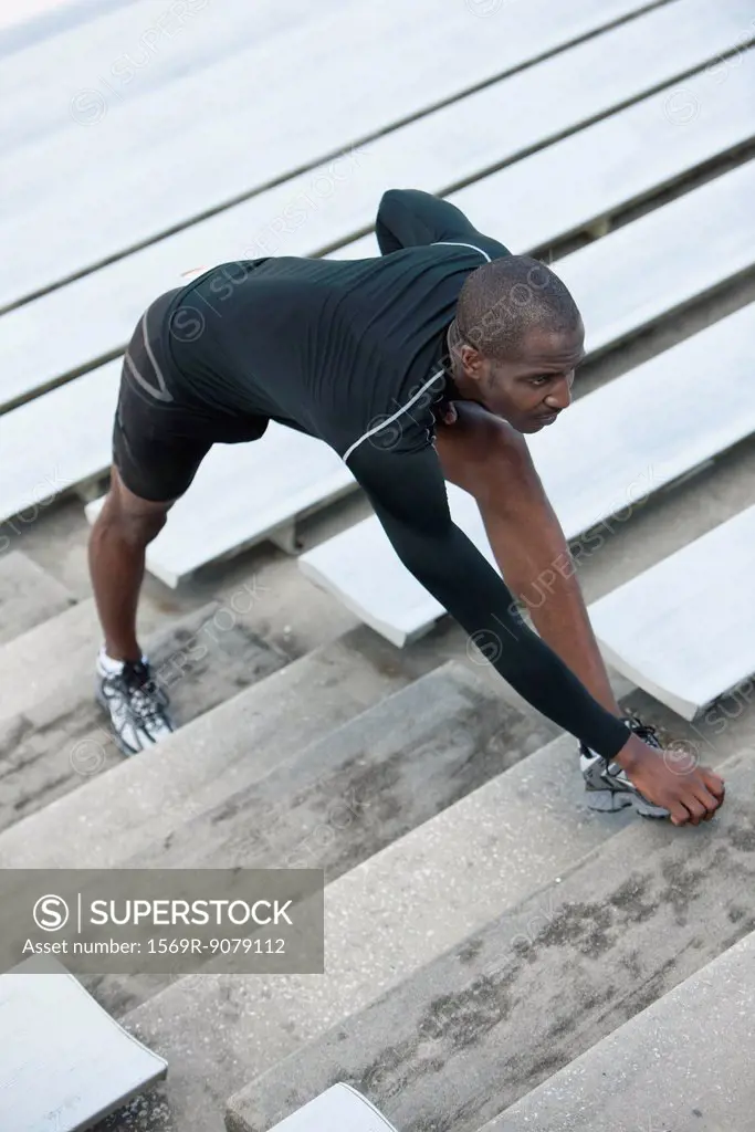 Man stretching on bleacher steps