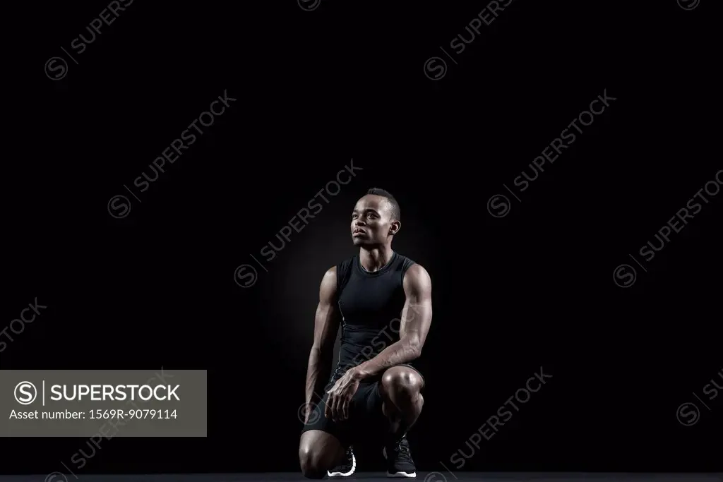 Athlete crouching, looking away in thought