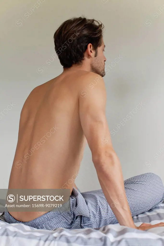 Man sitting on bed, rear view