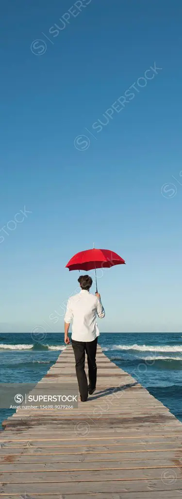 Man walking on pier with umbrella
