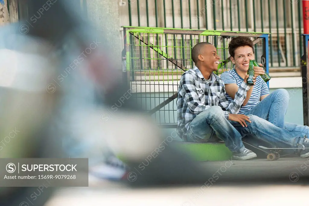 Friends sitting on sidewalk toasting