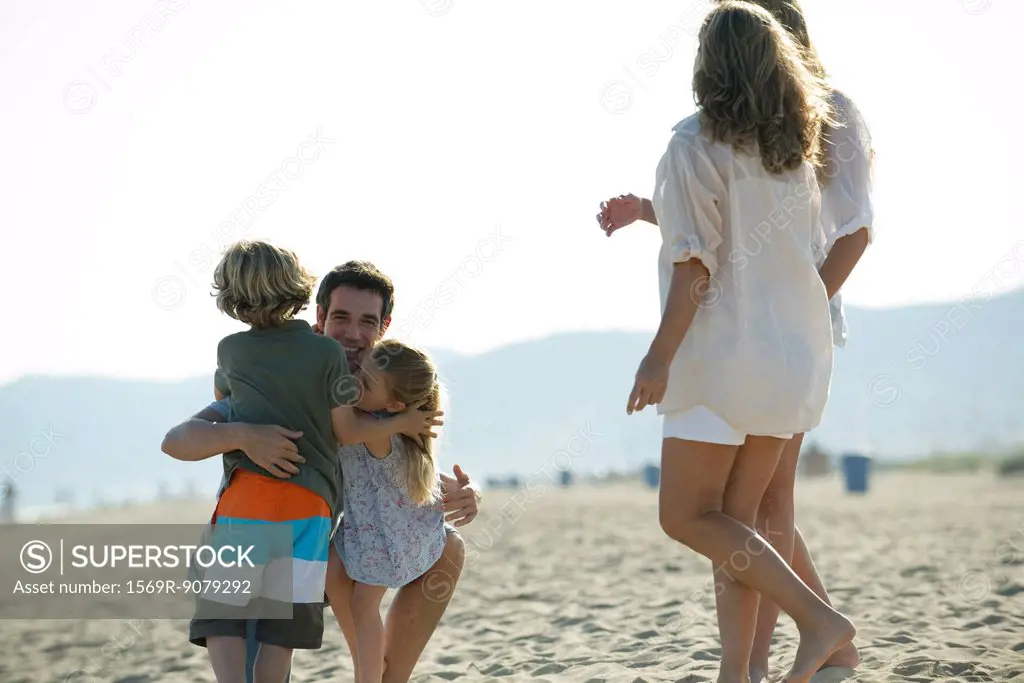Father embracing young children at the beach