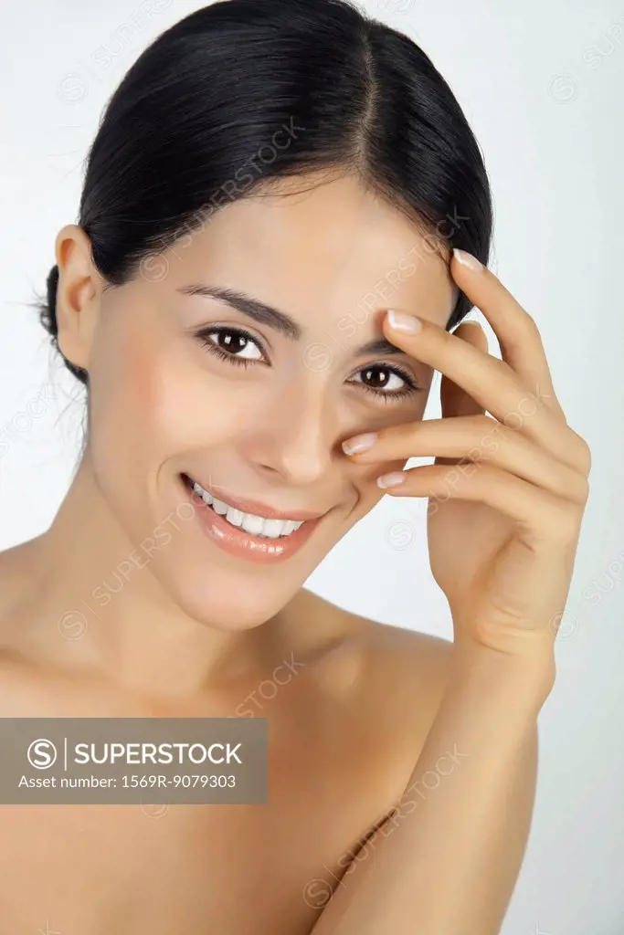 Woman touching face, looking through fingers at camera