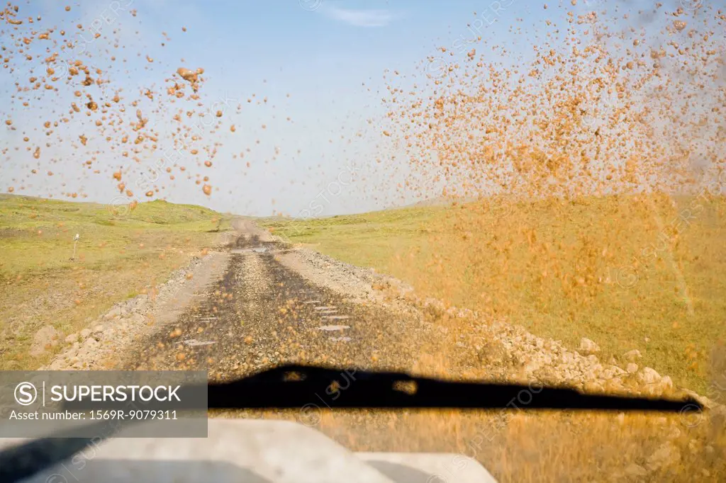 Dirt road viewed through muddy car windshield
