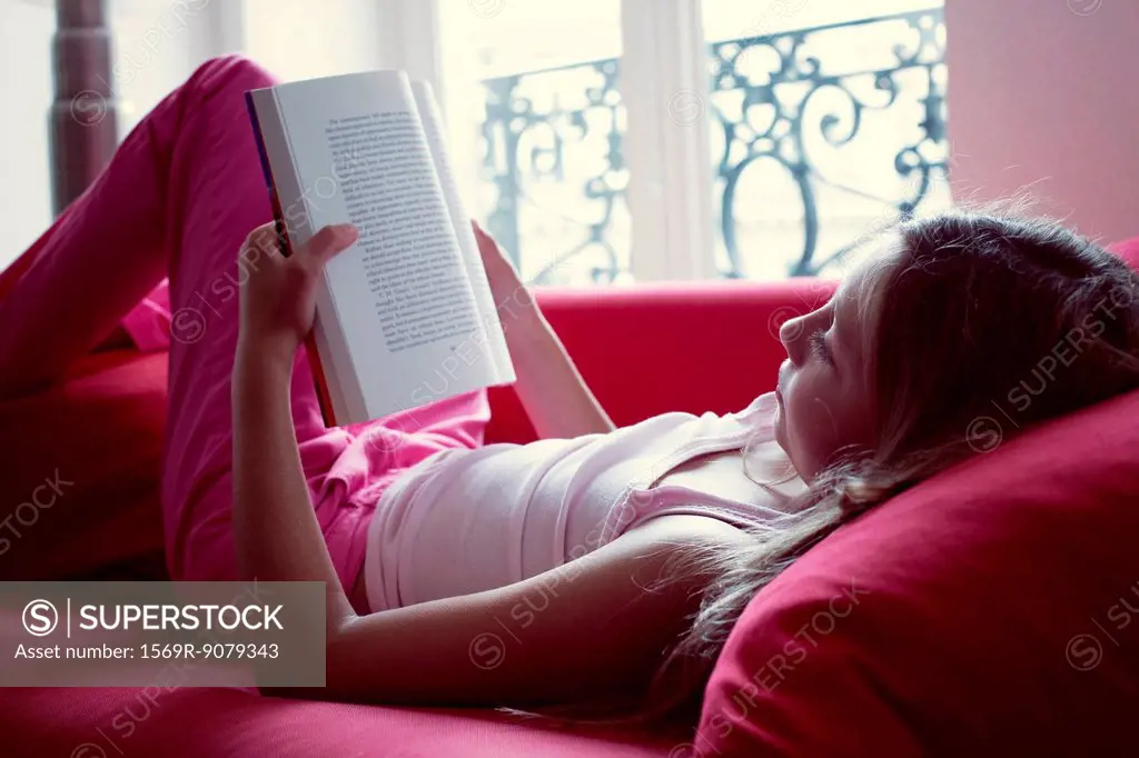 Girl reading book on couch