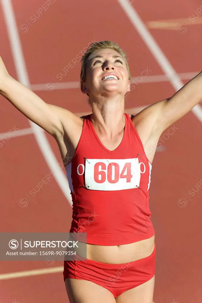 Woman running on track with arms raised in victory