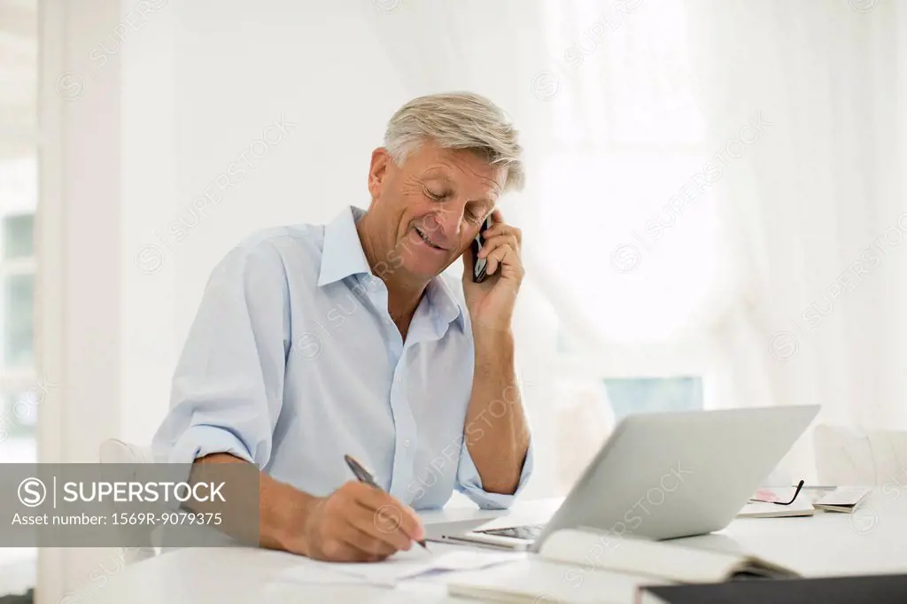 Man working at home, talking on cell phone