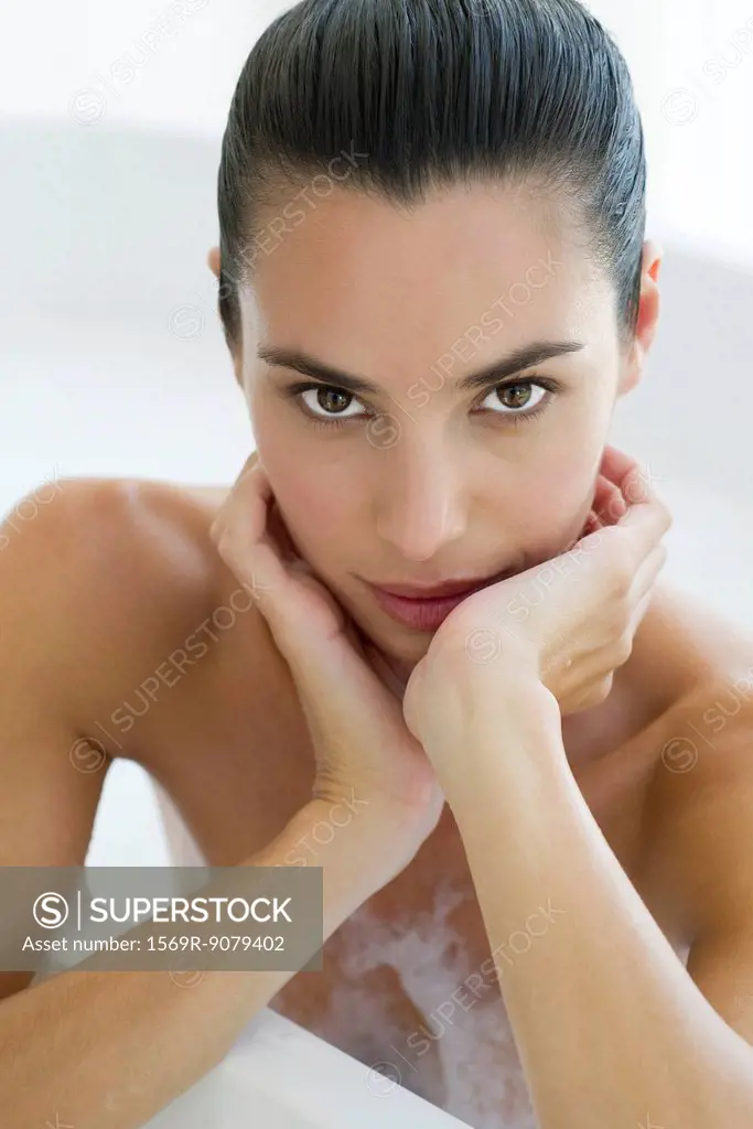 Woman in bath, leaning against edge of bathtub