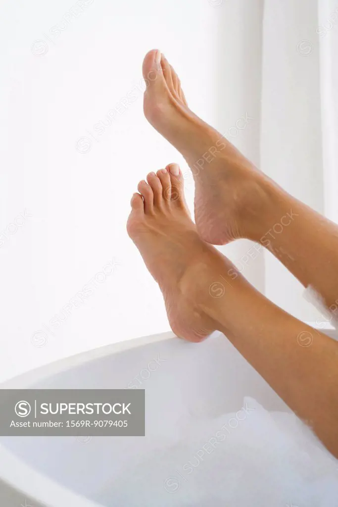 Woman´s legs resting on edge of bathtub, low section