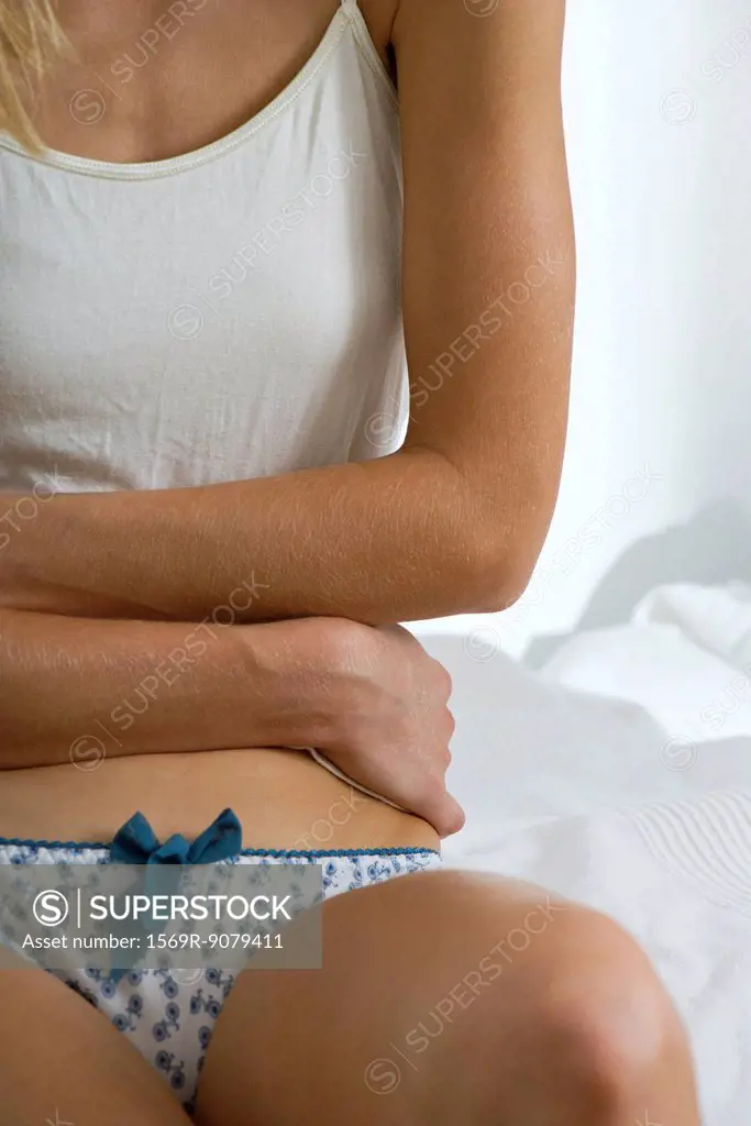 Woman with arms across abdomen, mid section