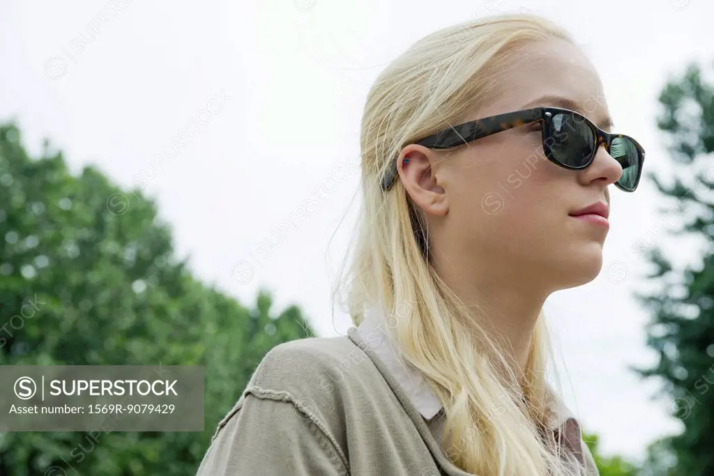 Young woman wearing sunglasses, looking away in thought