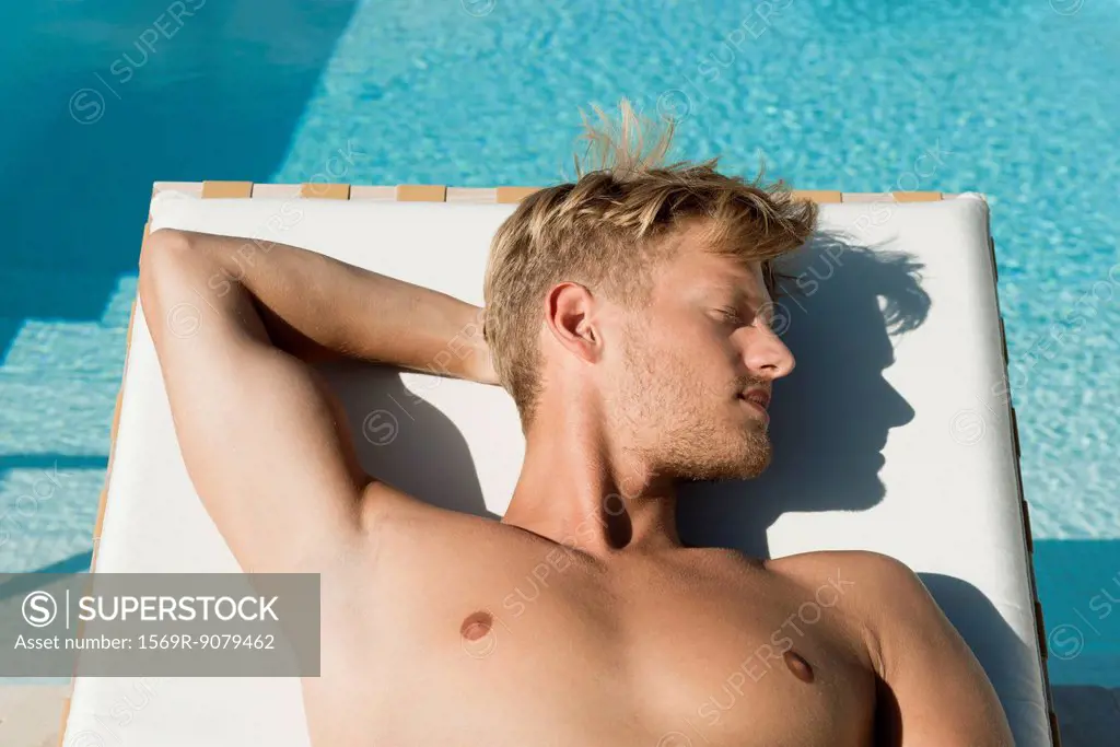 Man sunbathing beside pool
