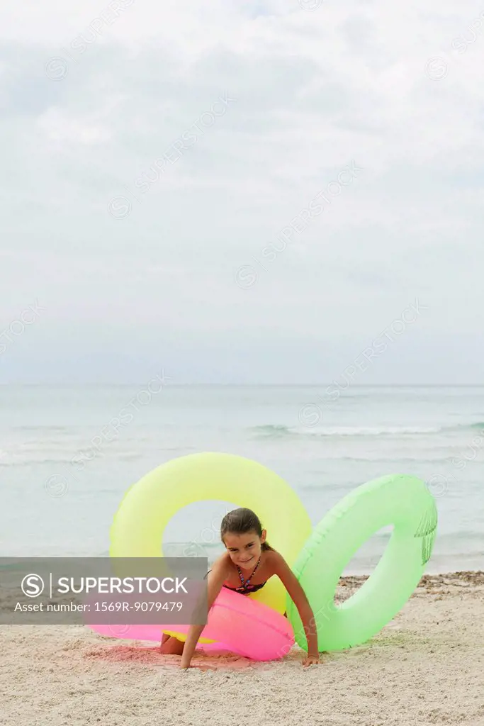 Girl playing with inflatable rings on beach