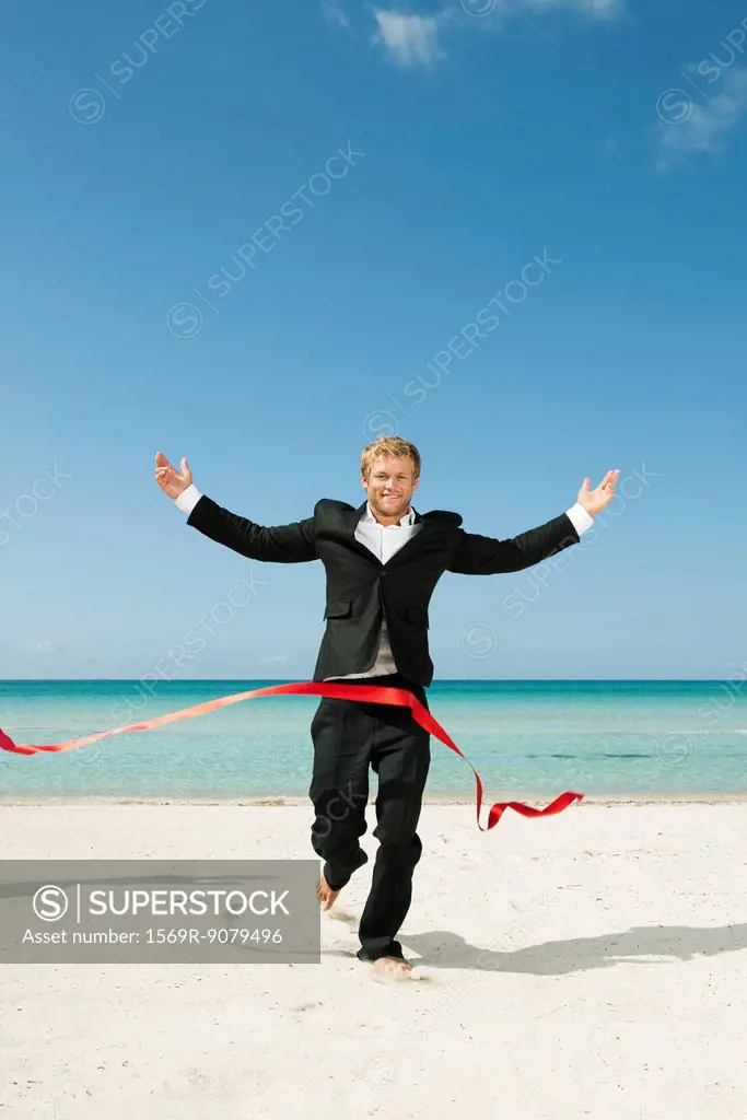 Young businessman running on beach towards finishing line
