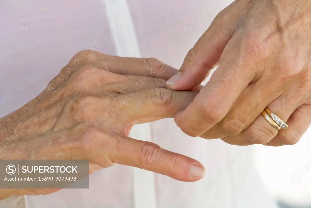 Senior woman rubbing knuckles, cropped