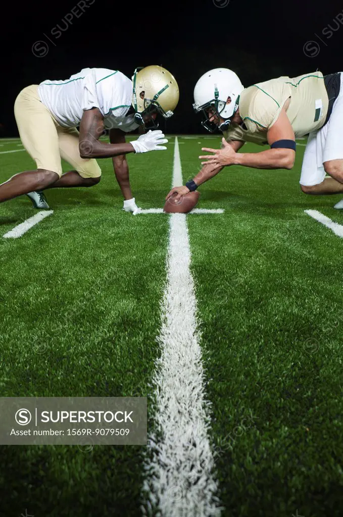 Opposing football players crouched at line of scrimmage