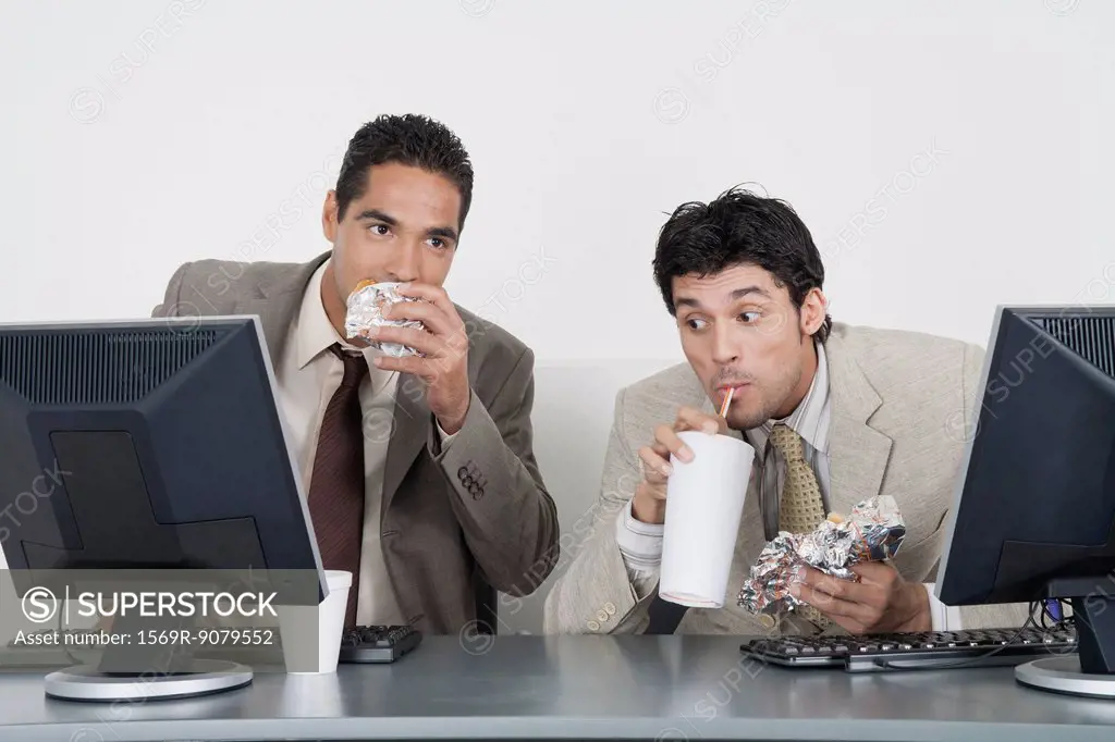 Businessmen eating fast food at desk in office