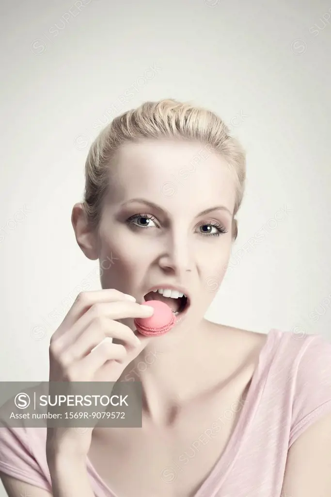 Young woman eating macaroon, portrait