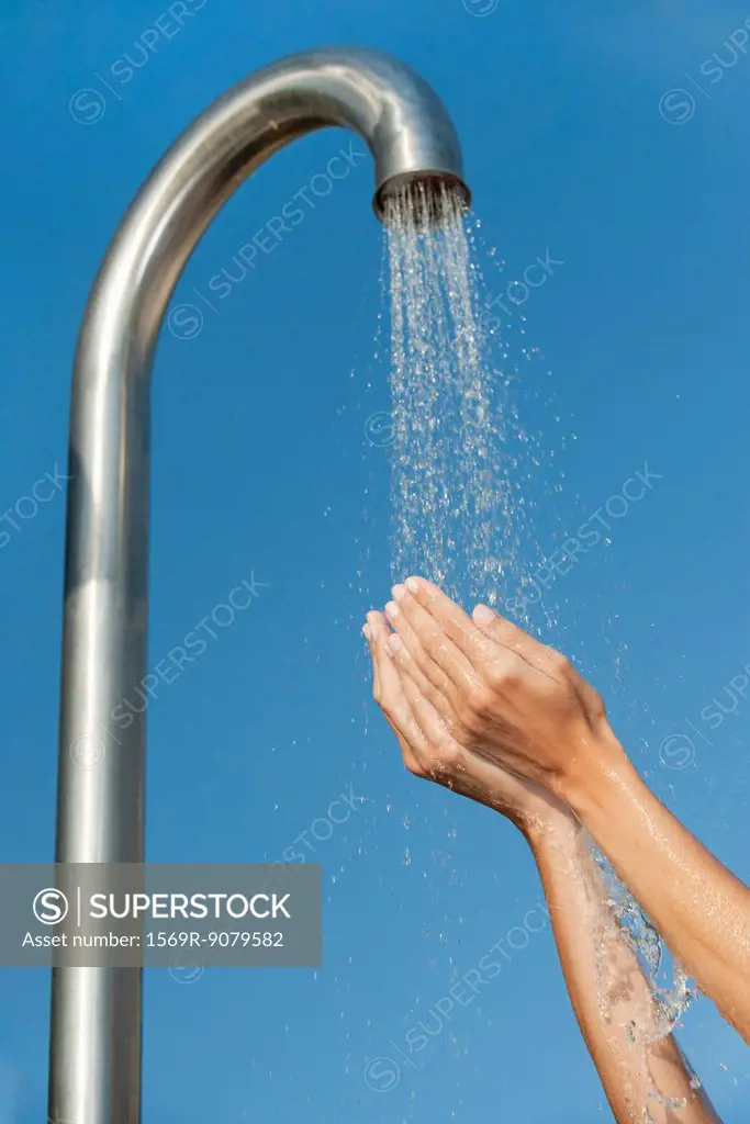 Person holding hands under public shower