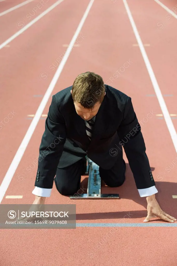 Businessman crouching at starting line on running track