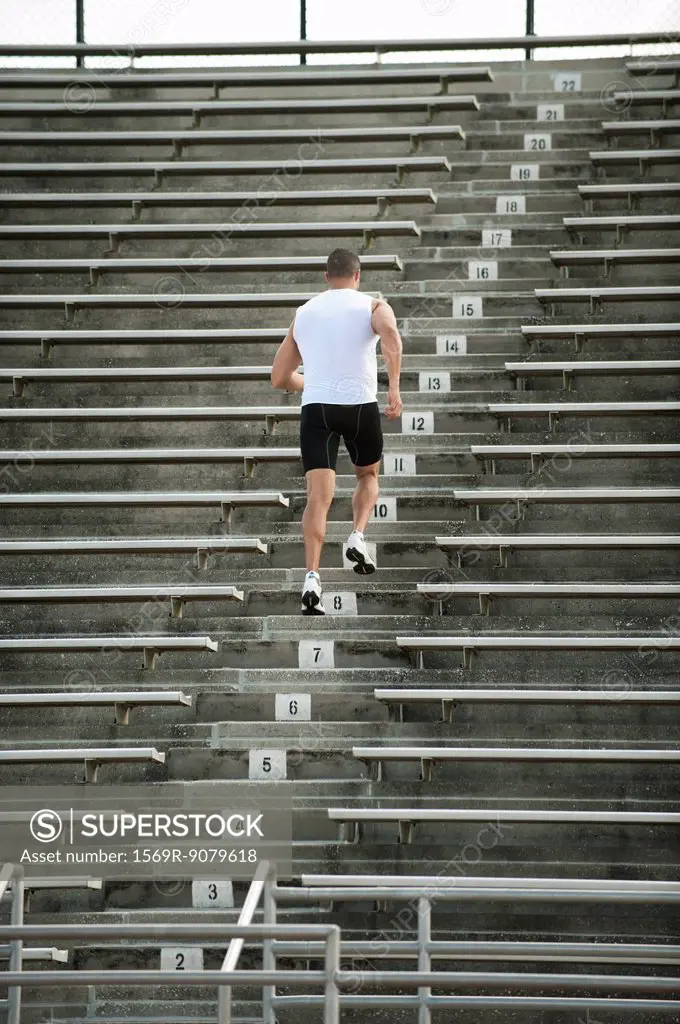 Man running up steps in stadium, rear view